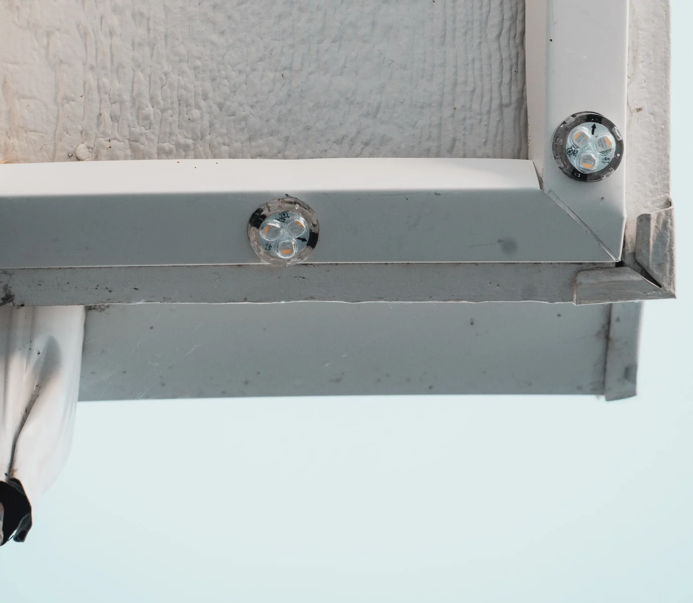 Unlit LED lenses fitted into aluminum track around a soffit corner